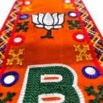 "Close-up view of BJP embroidered muffler showcasing lotus symbol, letter B, and colorful threadwork on orange fabric"