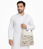 Indian man in white kurta with Warli art canvas shoulder bag.