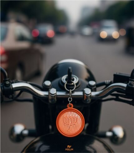 First-person view of bike handle with BJP plastic keychain hanging from ignition key, city traffic blurred in background