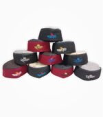 Stack of assorted Mahakal Himachali caps in red, grey, and black colors with embroidered religious text.