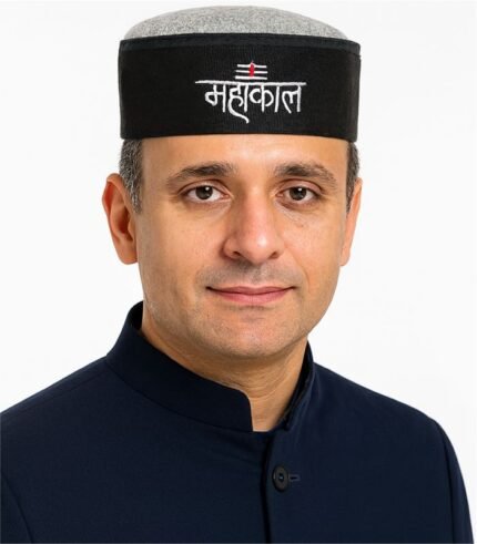 Indian man wearing a black Mahakal Himachali cap with white embroidered text and red tilak symbol.