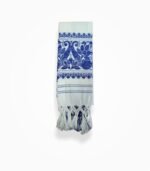 “Folded Assamese gamcha with blue woven floral pattern and tassels”