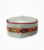 Traditional Himachali cap with red, green, and yellow embroidered band on light grey fabric.