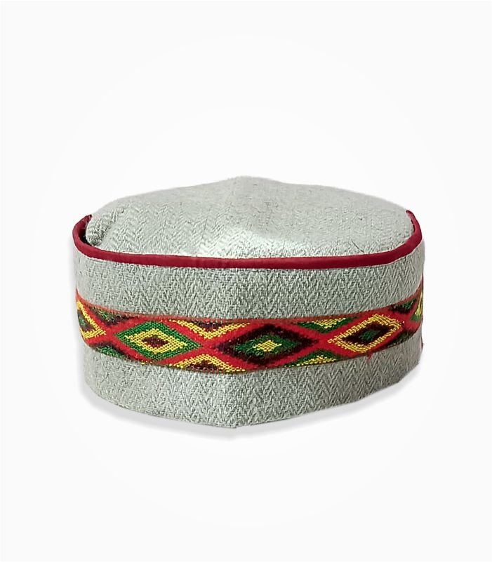 Traditional Himachali cap with red, green, and yellow embroidered band on light grey fabric.