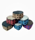 Assorted Himachali caps in various colors and traditional woven patterns stacked on a white background.