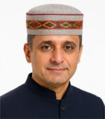 Middle-aged Indian man wearing a grey Himachali cap with red, yellow, and green center embroidery.