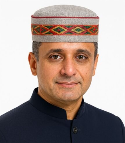 Middle-aged Indian man wearing a grey Himachali cap with red, yellow, and green center embroidery.
