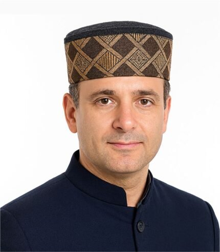 Indian man wearing a traditional Himachali cap and navy Nehru jacket, posing confidently.