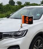 Hanuman Ji black orange car bonnet flag mounted on metal rod on white SUV hood